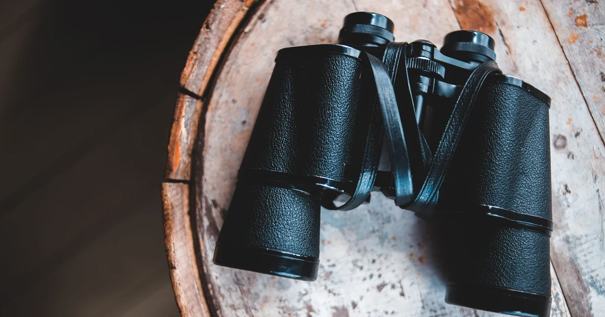 Binóculo apoiado sobre uma mesa de madeira