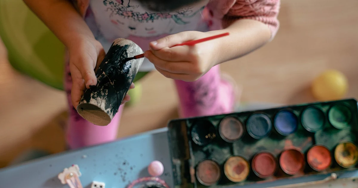Criança pintando um rolo de papel para decorar o binóculo caseiro